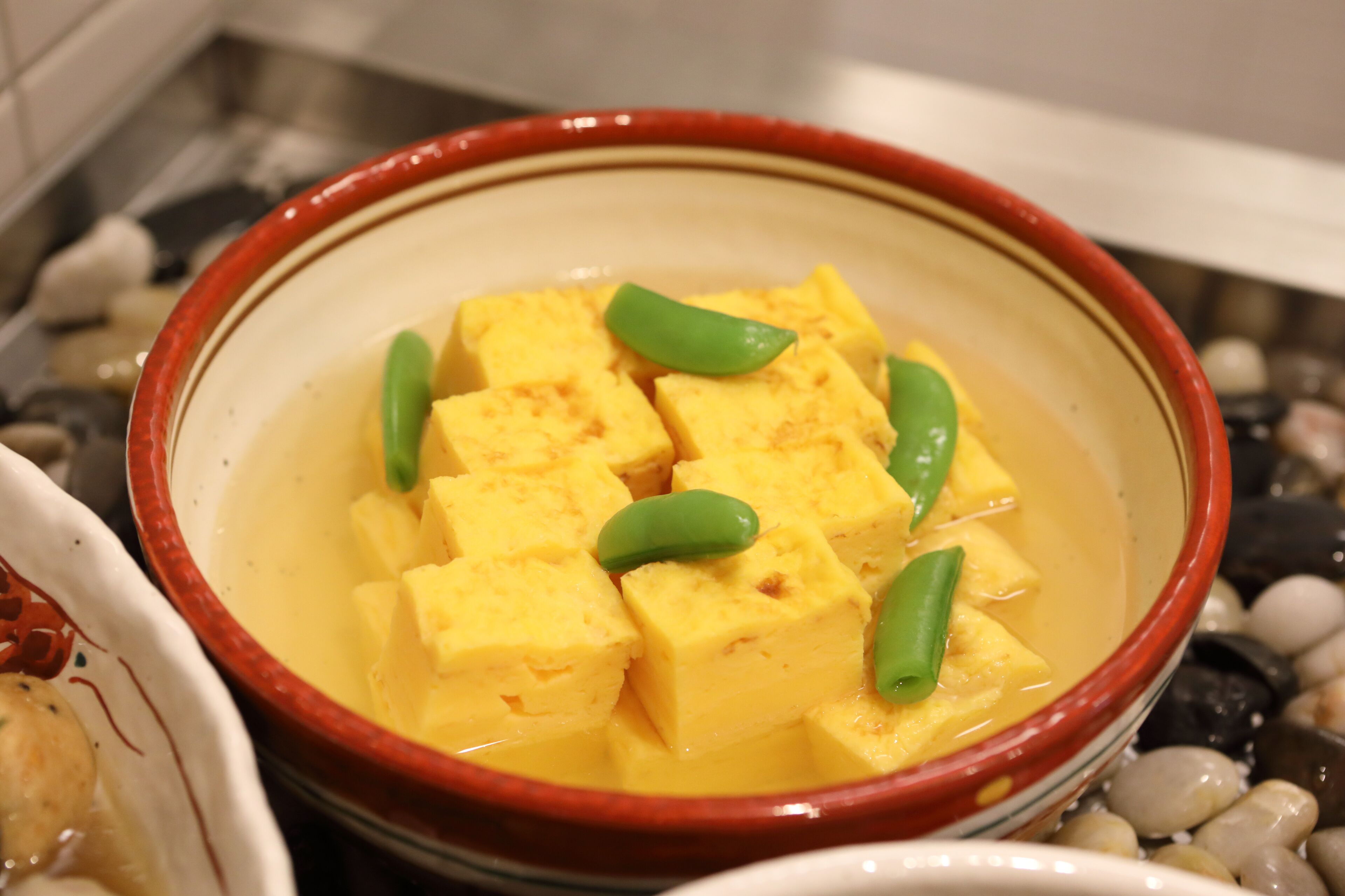 A bowl of tofu with green beans in a ceramic dish.