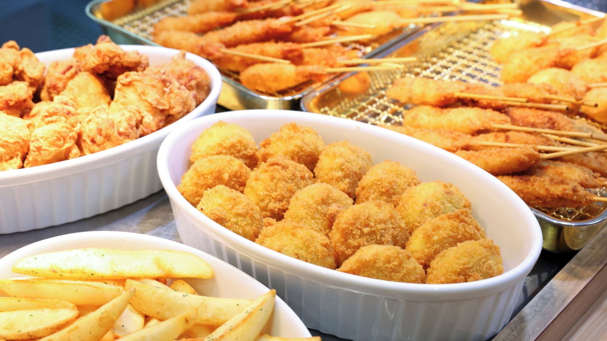 Un buffet proposant divers plats frits, notamment du poulet, du poisson et des frites.