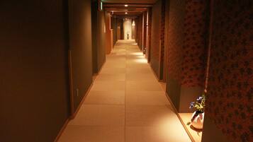 A long, narrow hallway with a tiled floor and patterned wallpaper on the walls.