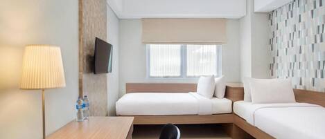 Habitación de hotel con cama, escritorio, silla, televisor y ventana con persianas.
