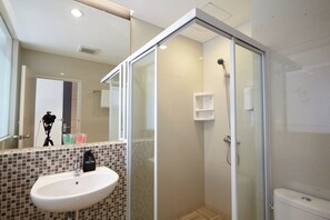 Une salle de bain moderne avec une douche à parois de verre, un lavabo avec un miroir et des toilettes.