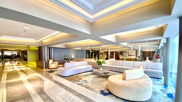 A spacious lobby with a marble floor, a large sofa, and a round ottoman. - All Nite & Day Hotel - Alam Sutera (South Tangerang)