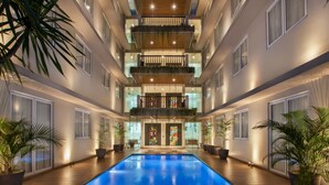A multi-story hotel with a central swimming pool, balconies with plants, and a modern interior design. - All Nite & Day Hotel - Alam Sutera (South Tangerang)