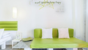 Ein modernes Schlafzimmer mit einem grünen Schlafsofa, einem kleinen Nachttisch und einer Wandleuchte.