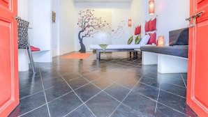 Ein modernes Interieur mit schwarzen Fliesen, einer weißen Bank und einer roten Tür.