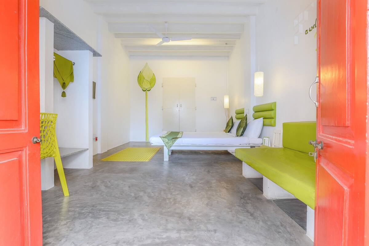 A room with a bed, a bench, a chair, and a door.