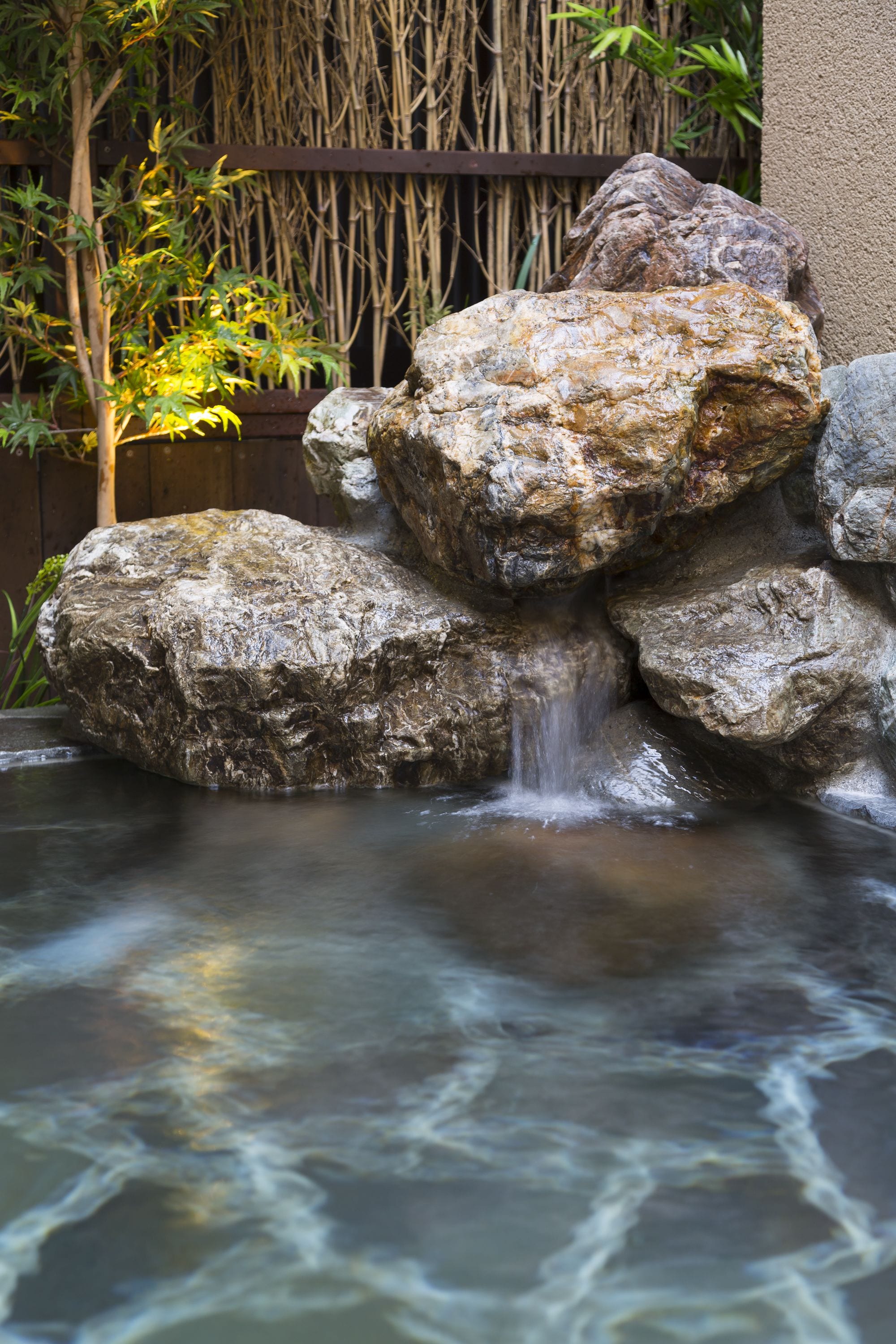 A rock formation with a small waterfall in a garden setting.