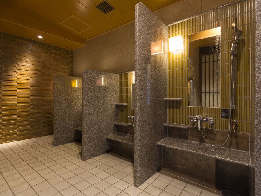 A public restroom with granite counters, a shower area, and a tiled floor.