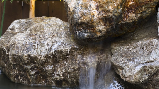 A rock formation with a small waterfall in a garden setting. - Dormy Inn Premium Tokyo Kodenmacho Hot Spring (Tokyo)