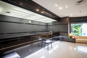 Uma área de recepção com um balcão preto, um banco e um sofá.