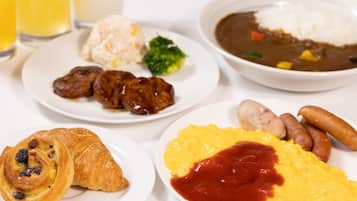 Un plato de desayuno con huevos, salchichas, cruasanes y un bol de sopa.