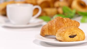 A plate with a croissant and a cup of coffee on a white table.