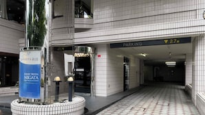 Entrada de hotel con piso de baldosas, señal de estacionamiento y cartel del Court Hotel Niigata.