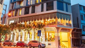 Een luxe hotel met meerdere verdiepingen, balkons, een goed verlichte ingang en een zichtbaar bord.