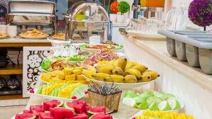 Een buffet met verschillende soorten fruit en gerechten, een koffiecorner en een raam met uitzicht.