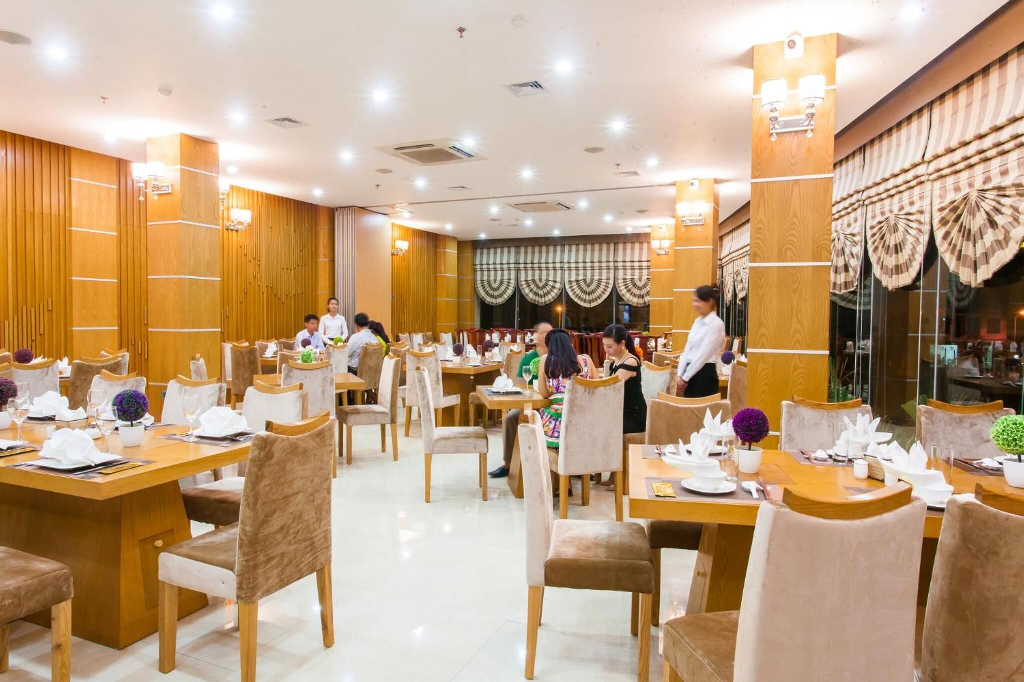 Un restaurante espacioso con paneles de madera, varias mesas y sillas.