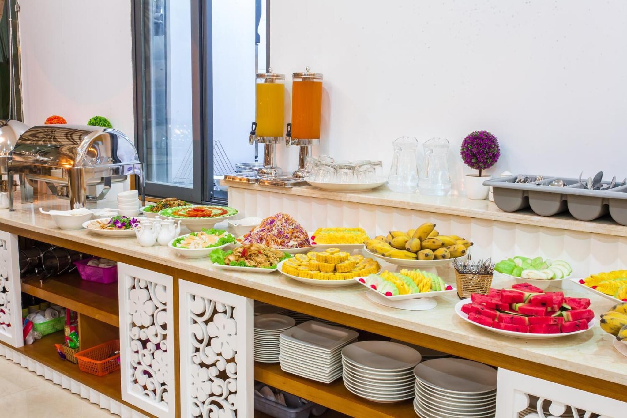 Montaje tipo bufé con diferentes alimentos y dispensadores de bebidas.