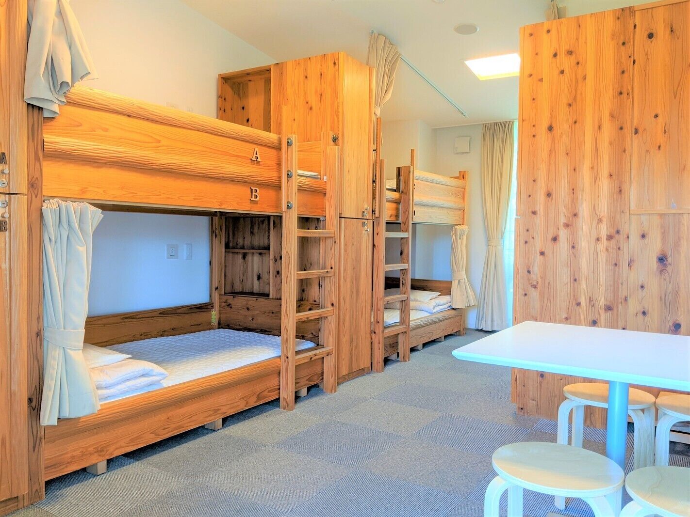 A bunk bed room with wooden walls, a table, and two chairs.