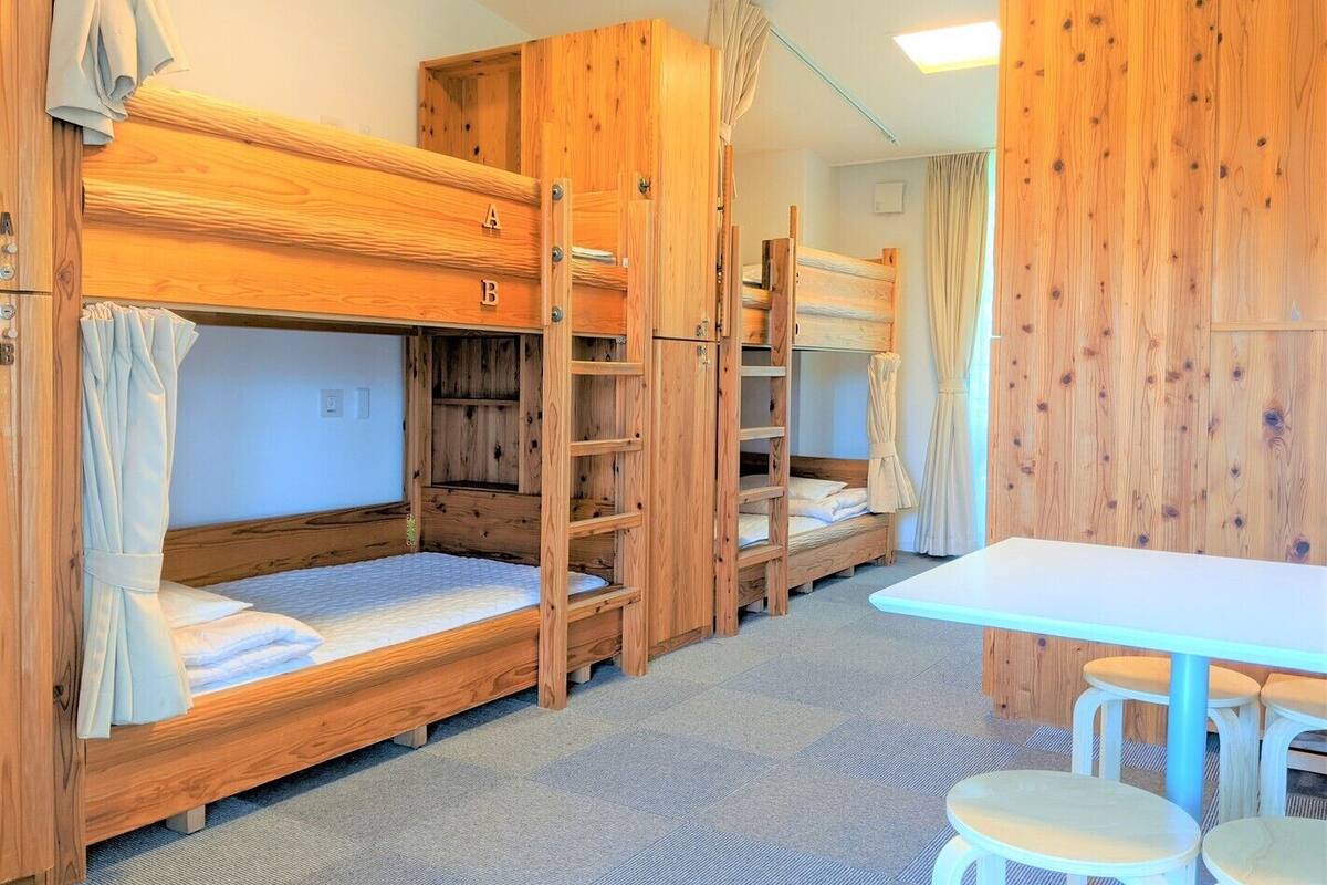 Dormitorio con literas, paredes de madera, una mesa y dos sillas.