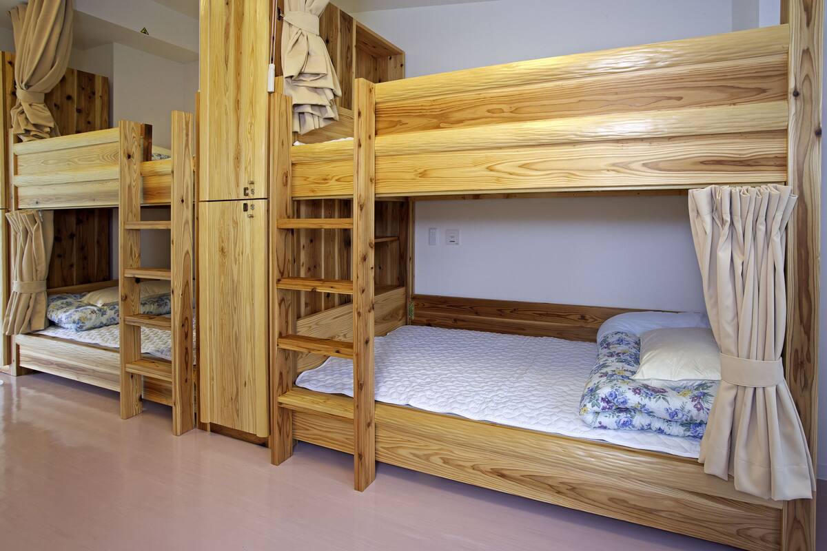 Habitación con literas de madera y una escalera.