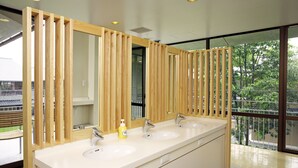 Un baño moderno con dos lavamanos, listones de madera y un ventanal grande.