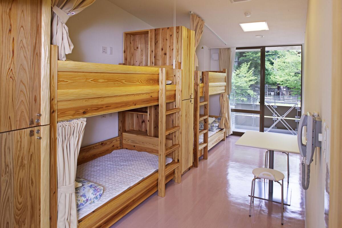 Habitación con literas de madera, una mesita pequeña y una silla.