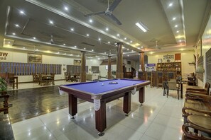 A billiards room with a pool table, chairs, and ceiling fans.