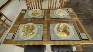 A dining table with four plates of food, surrounded by wooden chairs. - DV Angkor Villa (Siem Reap)