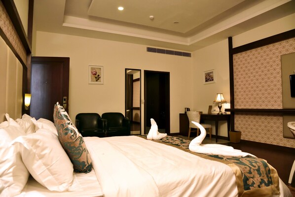 A hotel room with a large bed, a desk, a chair, and a bathroom. - The Fern Hillside Resort Bhimtal (Nainital)