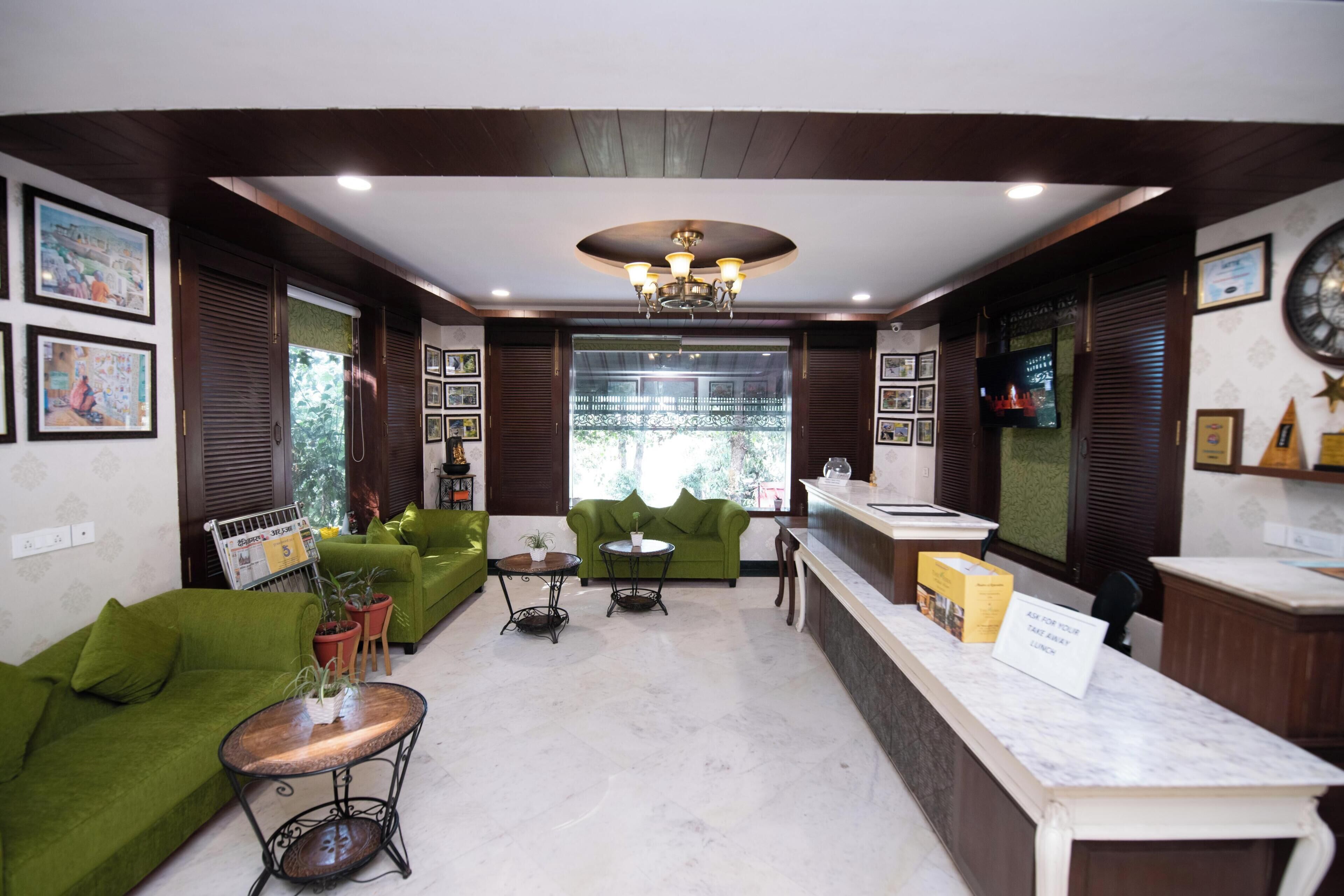 A hotel lobby with green sofas, a reception desk, and a chandelier.