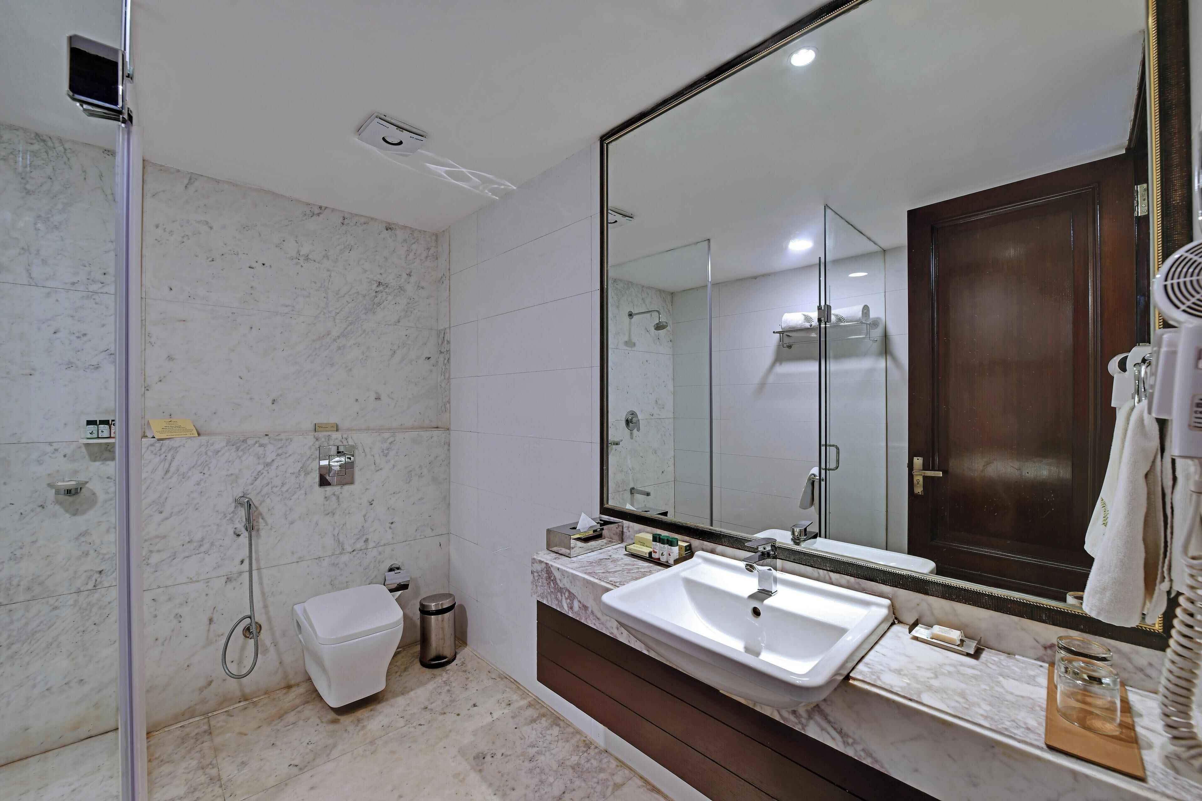 A modern bathroom with a large mirror, a shower, and a sink.