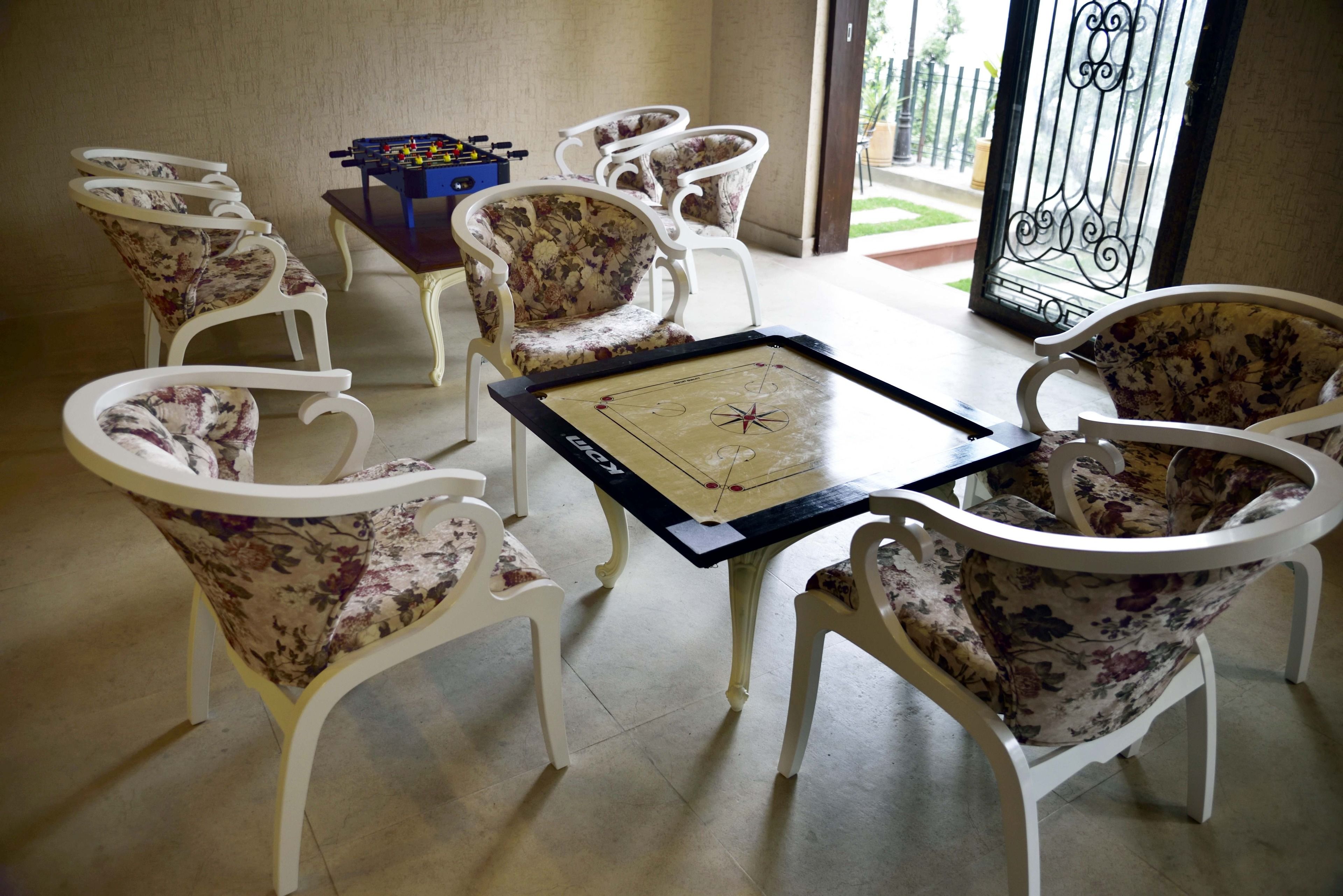 Una habitación con mesa de futbolín, sillas estampadas y mesa de tenis de mesa.
