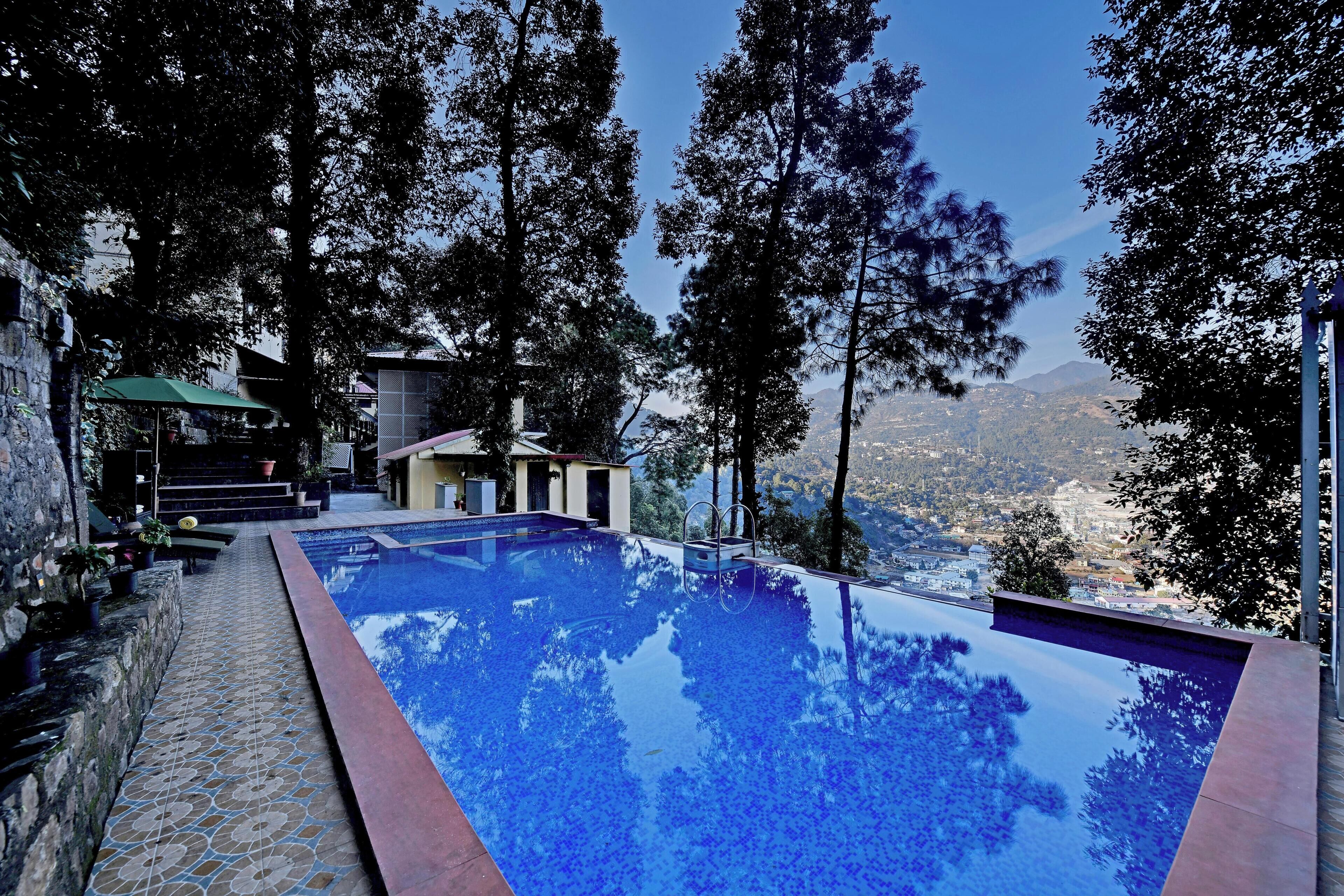 A swimming pool with a clear view of the surrounding landscape, including trees and distant buildings.