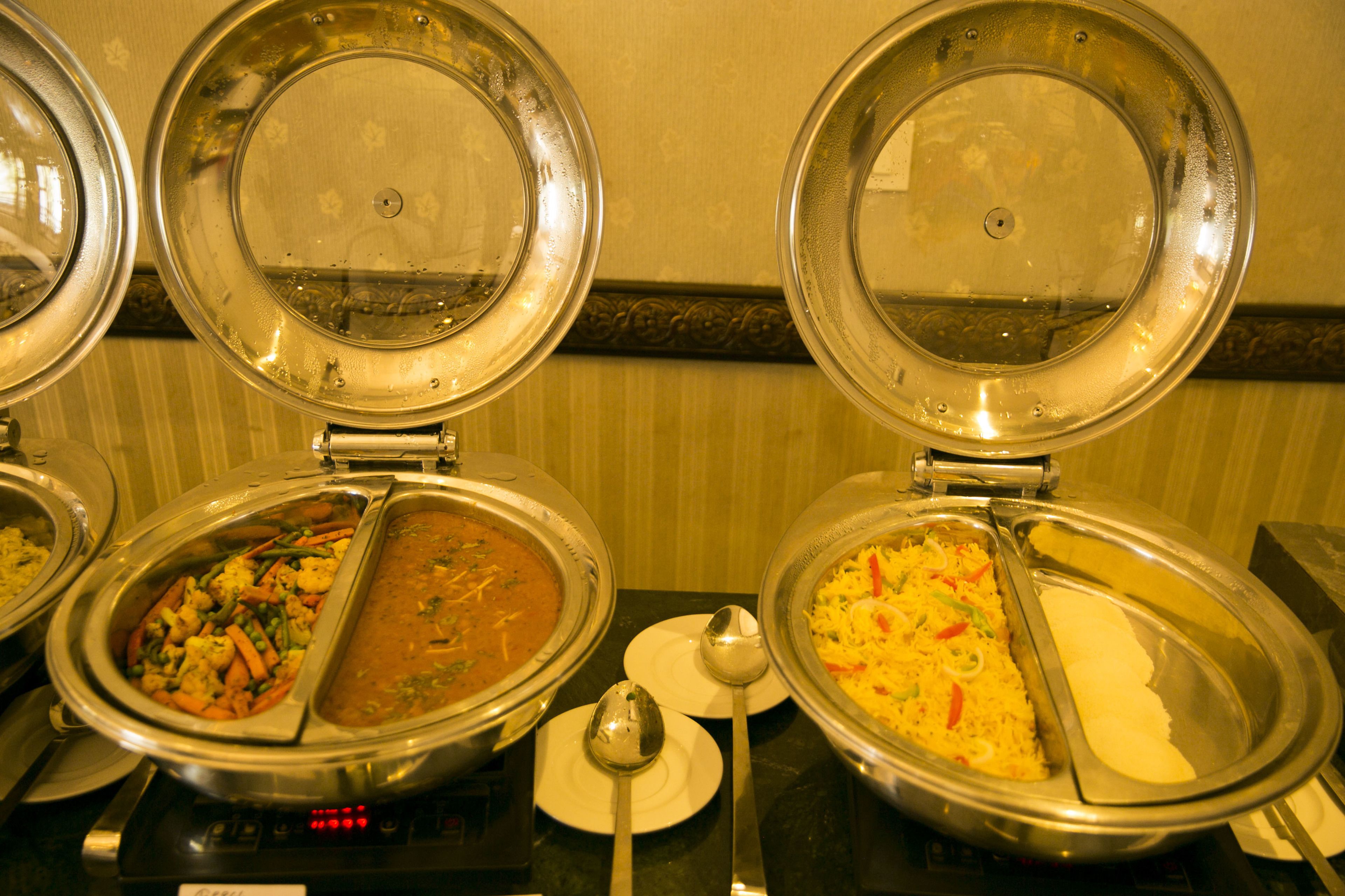 A buffet with various dishes, including rice, vegetables, and a curry.