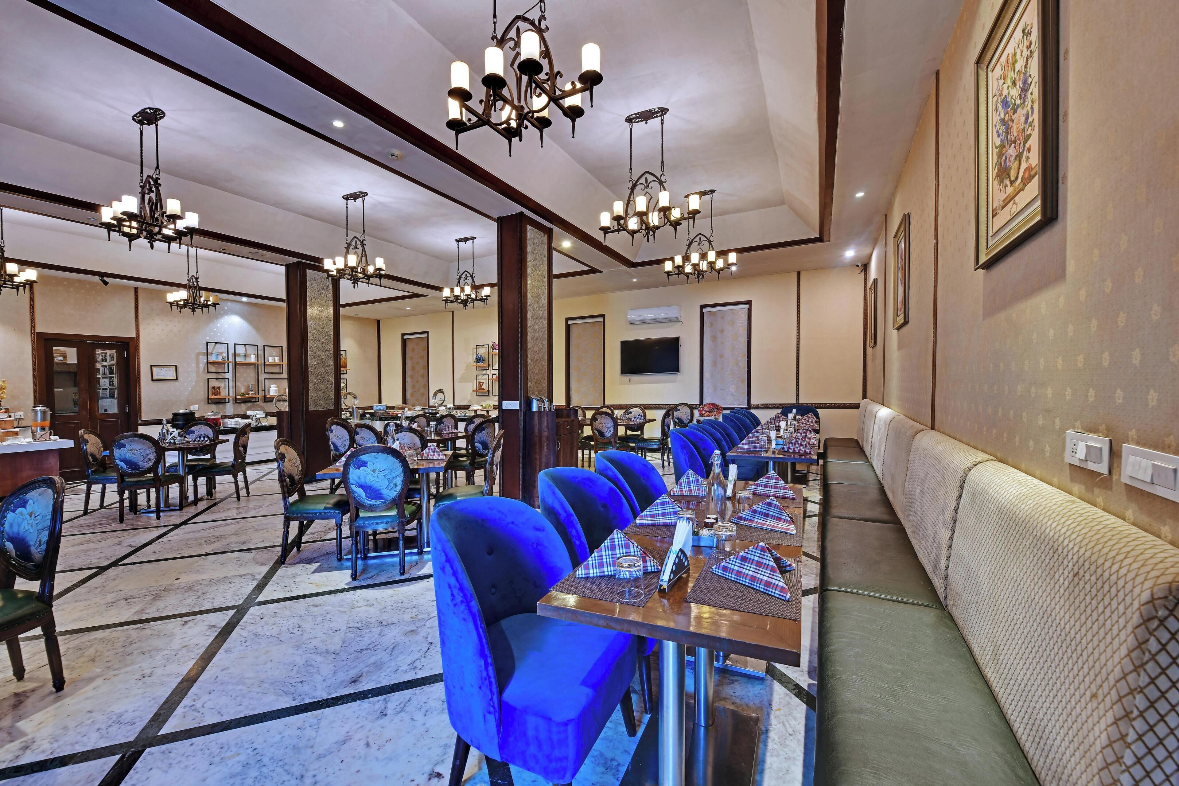 A hotel dining area with multiple tables, chairs, and a long bench along the wall.
