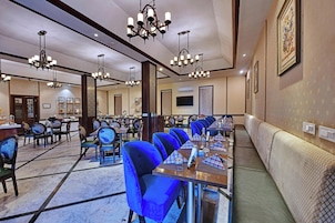 Une salle à manger d’hôtel avec plusieurs tables, des chaises et un long banc le long du mur.