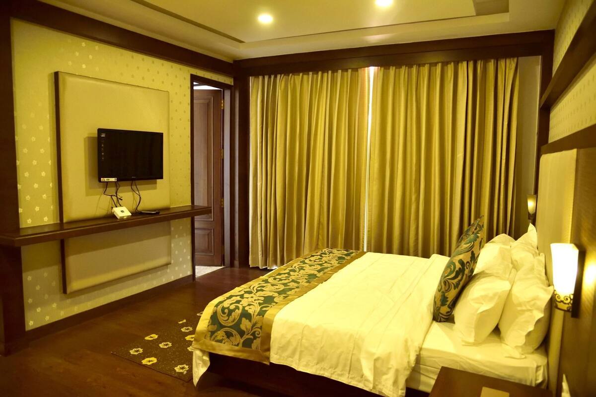 Een hotelkamer met een bed, een televisie aan de muur en een gordijn.