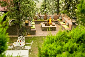 Un patio con un hogar para fuego, asientos y una mesa con sillas.