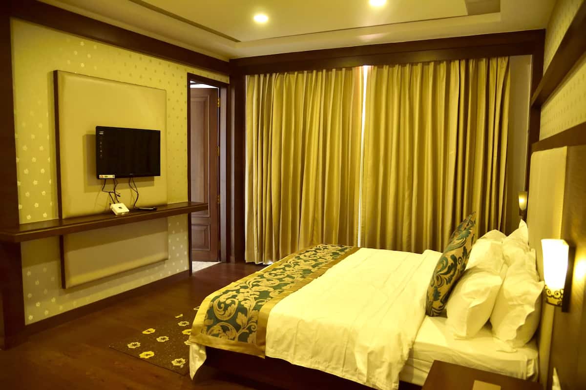 Een hotelkamer met een bed, een aan de muur bevestigde televisie en een gordijn.