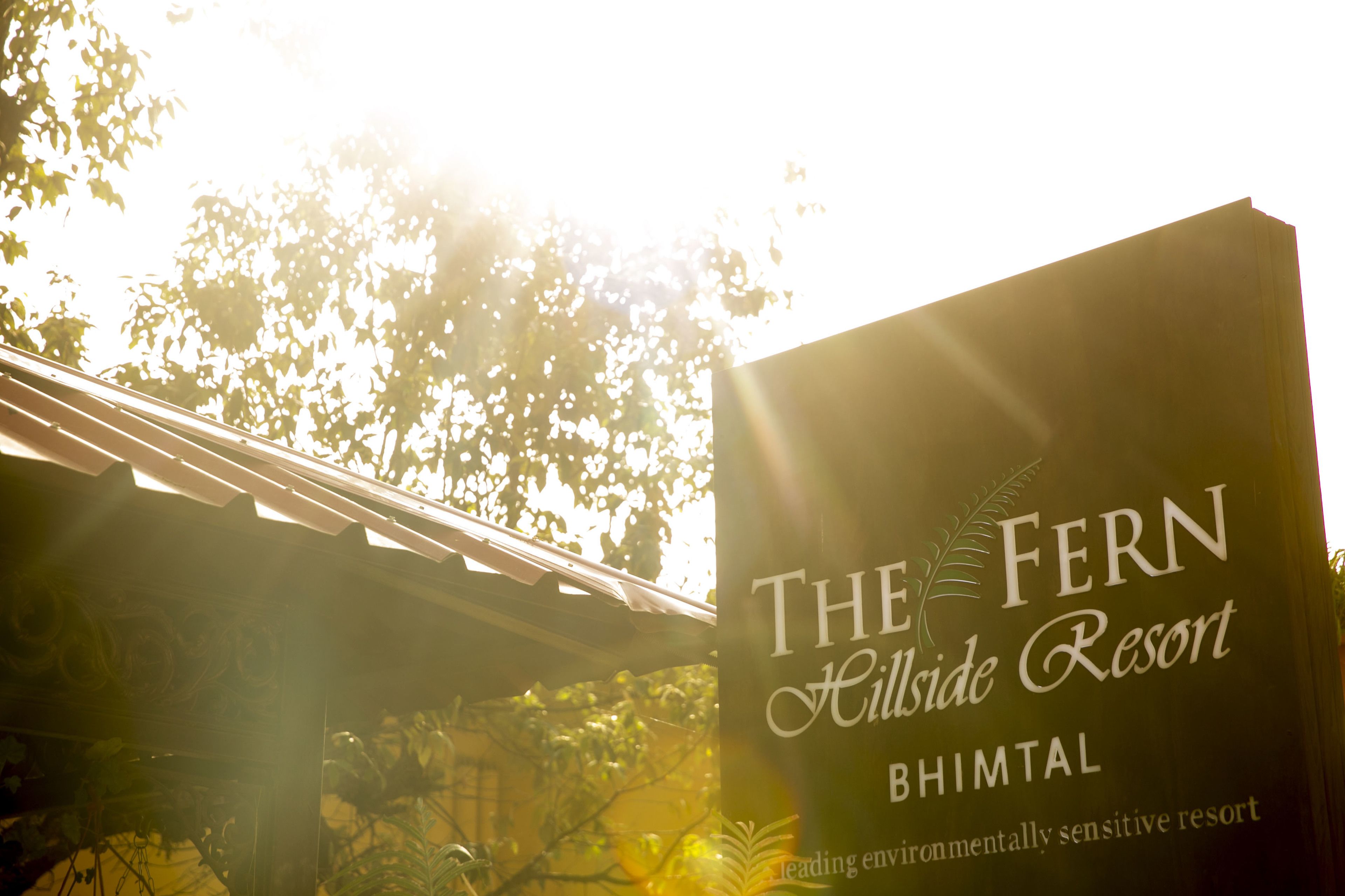 Une enseigne indiquant l’emplacement du complexe hôtelier The Fern Hillside Resort à Bhimtal, et soulignant son engagement en faveur de la protection de l’environnement.