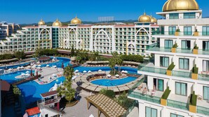 Ein Hotel mit mehreren Schwimmbecken, ein großes Gebäude mit goldenen Kuppeln und einem strahlend blauen Himmel.