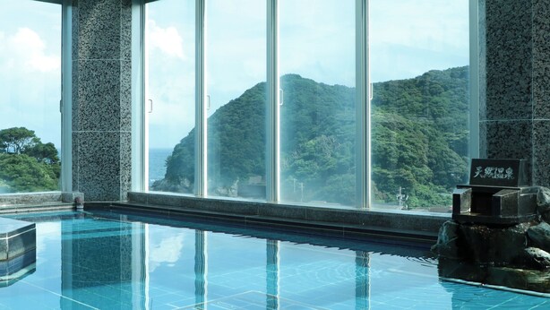 Une piscine offrant une vue sur un paysage montagneux grâce à de grandes baies vitrées.