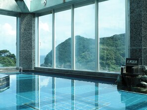 Piscina com vista para uma paisagem montanhosa através de grandes janelas.