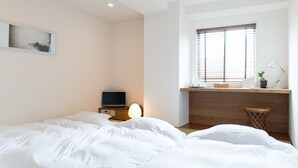 A bedroom with a bed, a desk, a computer, and a window with blinds. - Hotel Pacific Kanazawa (Kanazawa)