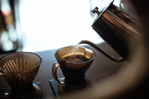 Eine Kaffeemaschine mit einer transparenten Glaskaraffe und einem Metallkessel, der Kaffee einschenkt.