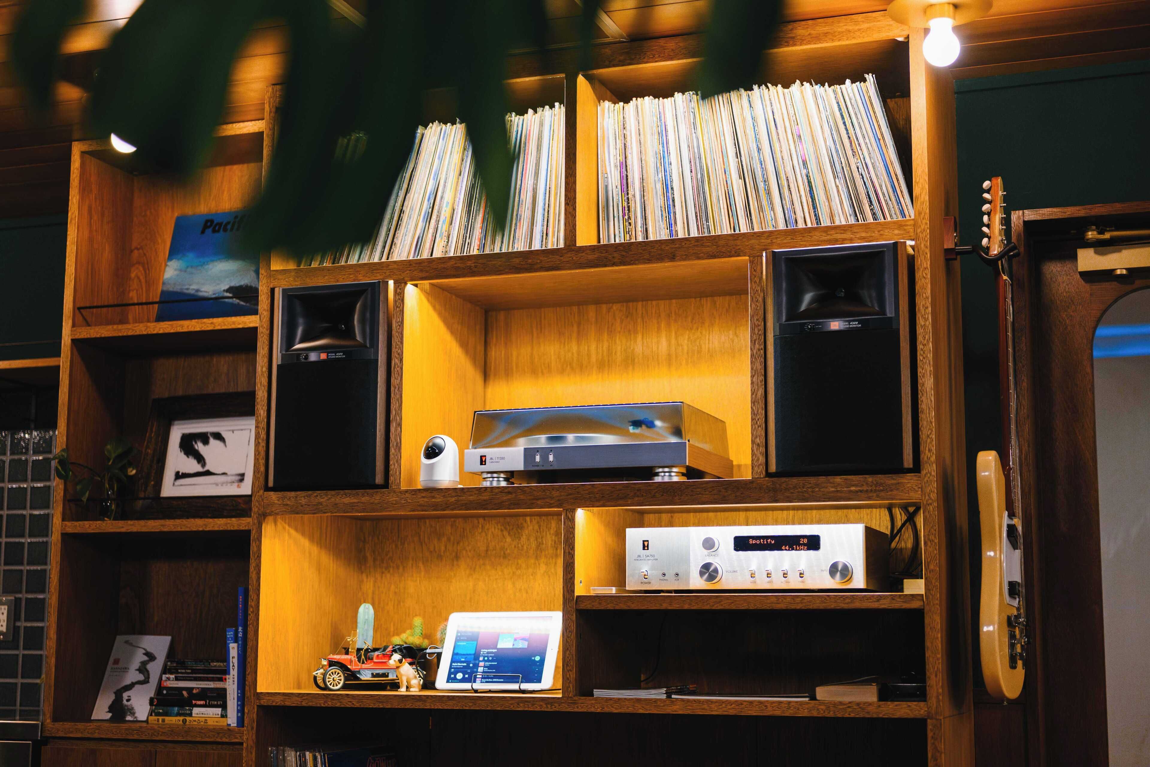 Una habitación con estanterías de madera que contienen libros, un tocadiscos y altavoces.