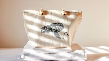 A canvas tote bag with a black embroidered design and the text "HOTEL PACIFIC."