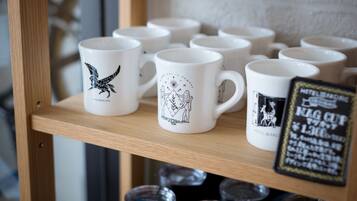 A display of white mugs with black designs on a wooden shelf.