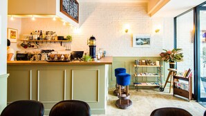 A bar area with a counter, shelves with bottles, a coffee machine, and a seating area with chairs and a stool. - Hotel Pacific Kanazawa (Kanazawa)