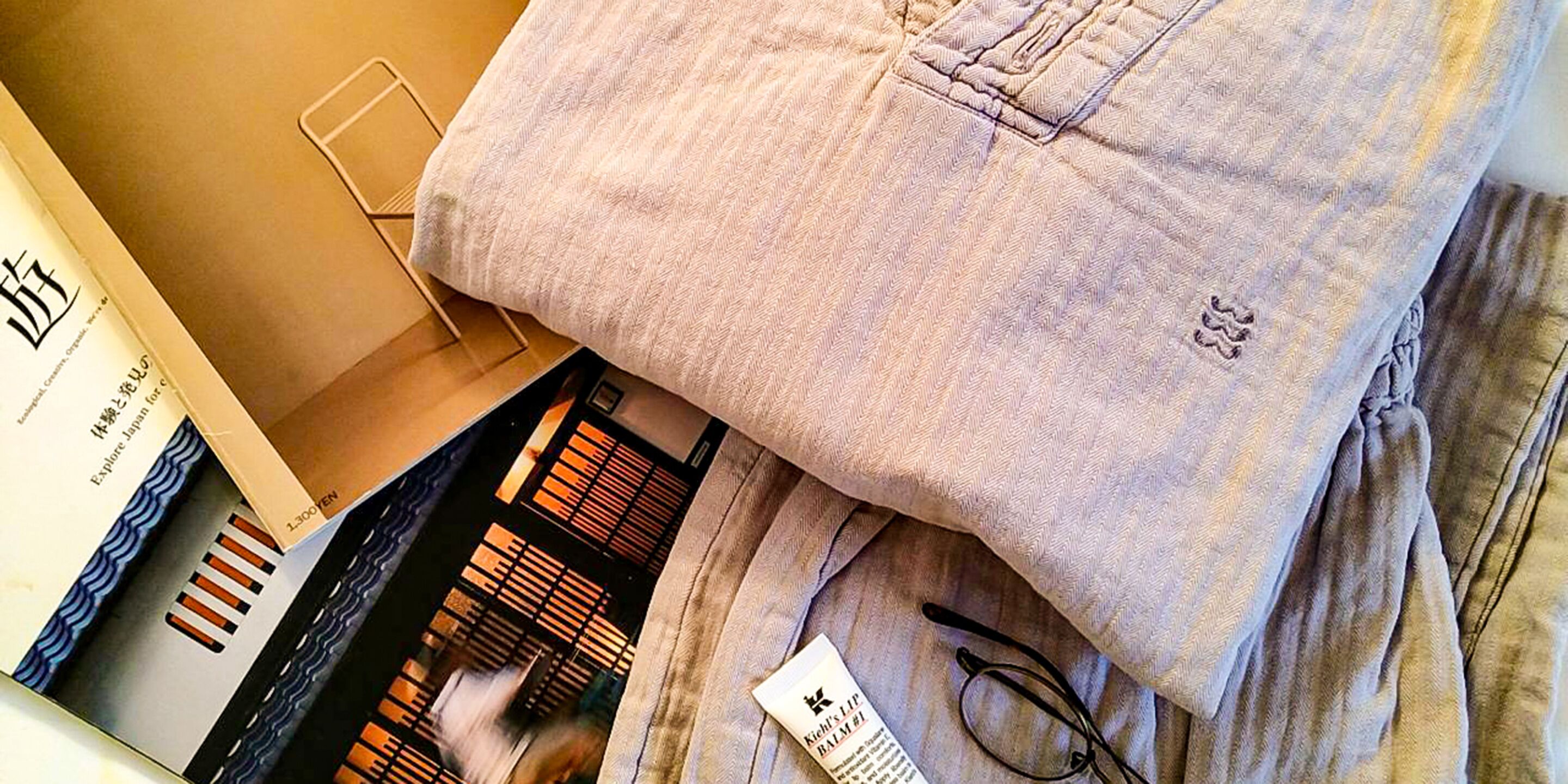 Ein ordentlich gefaltetes Handtuch und eine hellgraue Hose liegen auf einem Bett.